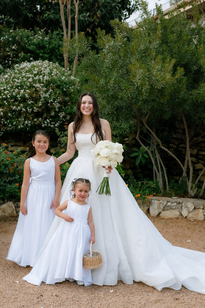 Flower girls in white dresses alongside wedding party in black at Villa Antonia Hill Country wedding