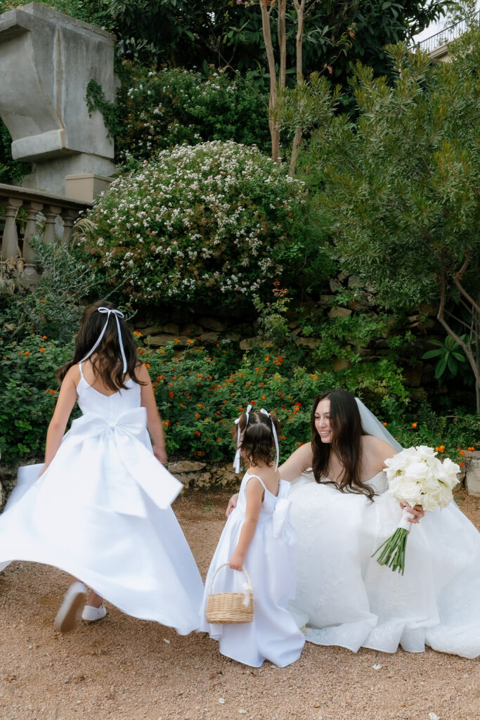 Flower girls in white dresses alongside wedding party in black at Villa Antonia Hill Country wedding