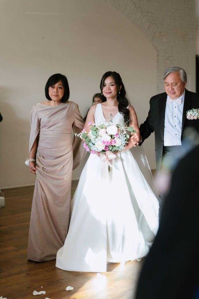 Bride walking down the aisle at One Eleven East in Hutto Texas surrounded by winter florals, captured by Andrea Jang Photography