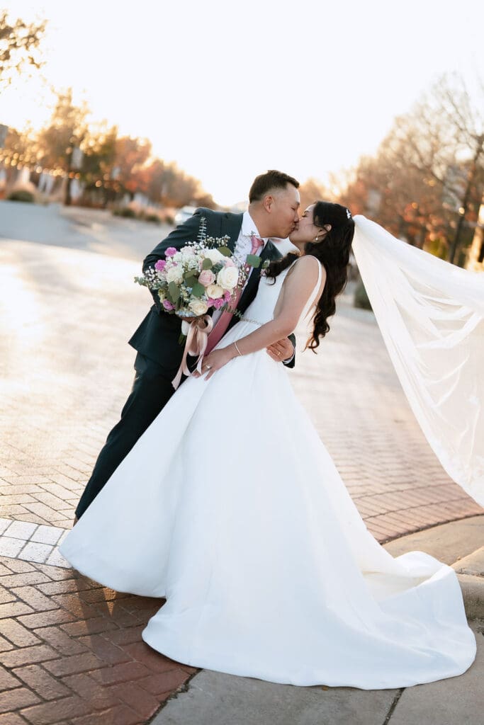 Newlyweds sharing a kiss during their winter wedding portraits at One Eleven East in Hutto Texas, photography by Andrea Jang
