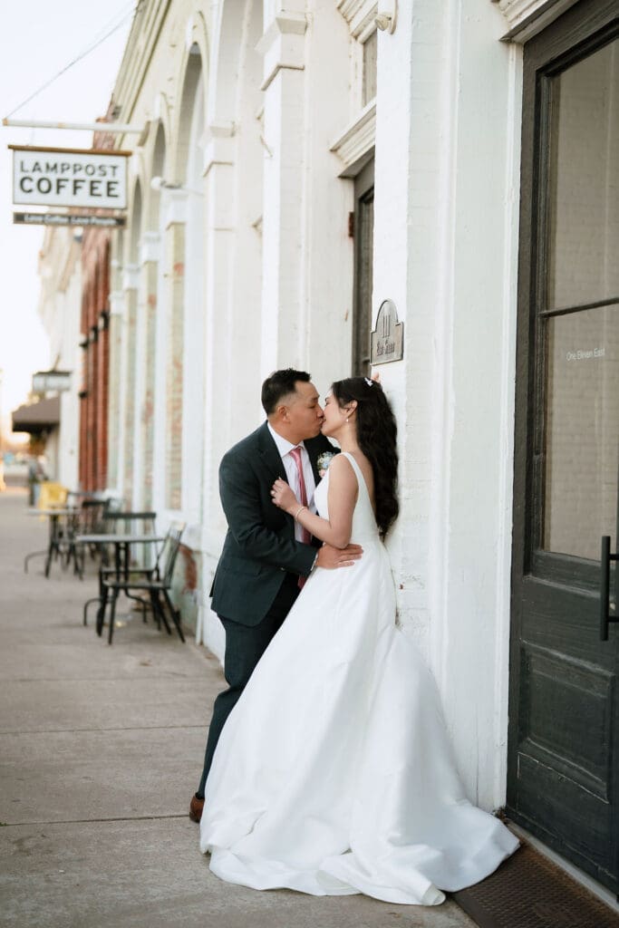 Newlyweds sharing a kiss during their winter wedding portraits at One Eleven East in Hutto Texas, photography by Andrea Jang