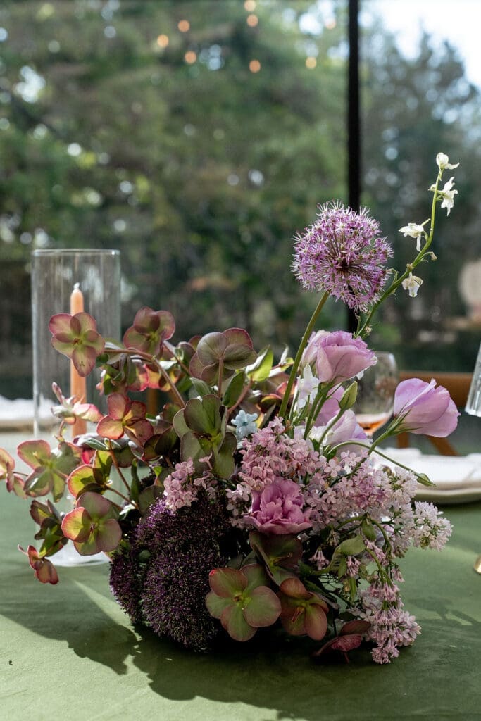 Close up of Monet inspired wedding floral arrangement with allium, lilac, blue hydrangea, blush lisianthus, and ranunculus at Wild Roots Texas Hill Country wedding venue