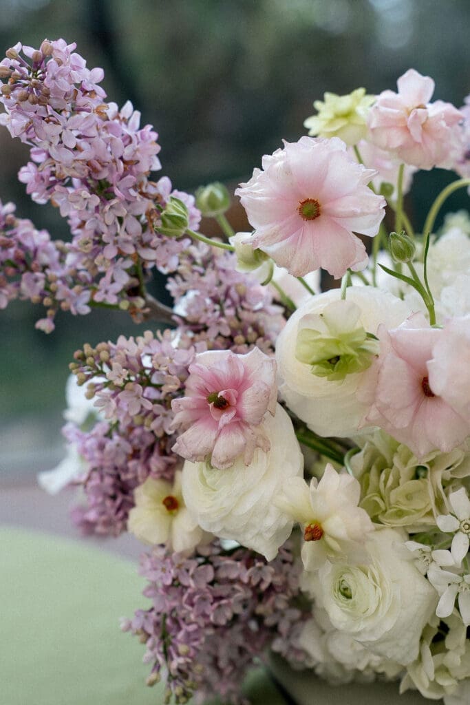 Close up of Monet inspired wedding floral arrangement with allium, lilac, blue hydrangea, blush lisianthus, and ranunculus at Wild Roots Texas Hill Country wedding venue