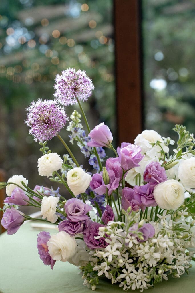Close up of Monet inspired wedding floral arrangement with allium, lilac, blue hydrangea, blush lisianthus, and ranunculus at Wild Roots Texas Hill Country wedding venue