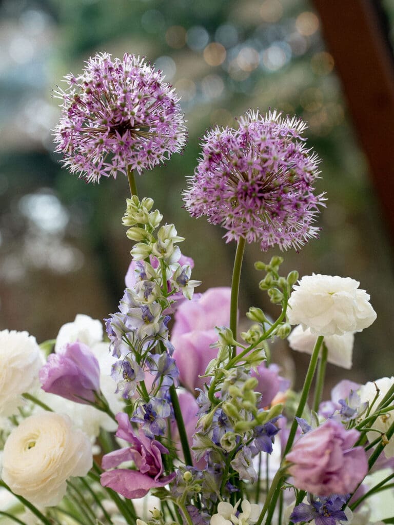 Close up of Monet inspired wedding floral arrangement with allium, lilac, blue hydrangea, blush lisianthus, and ranunculus at Wild Roots Texas Hill Country wedding venue