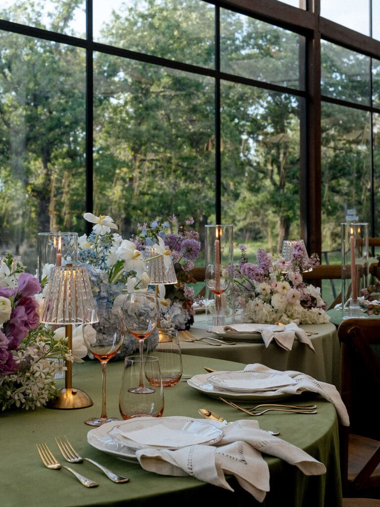 Monet inspired wedding reception tablescape with sage green velvet linens, impressionist floral centerpieces, and peach taper candles at Wild Roots Lockhart Texas, photographed by Austin wedding photographer Andrea Jang