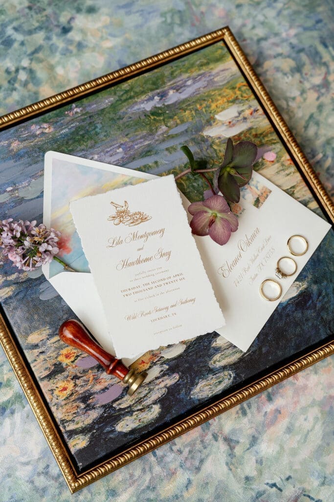 Monet inspired wedding invitation suite flat lay with watercolor envelope liner, wax seal, velvet ring boxes, and garden florals at Wild Roots Lockhart Texas by Austin wedding photographer Andrea Jang