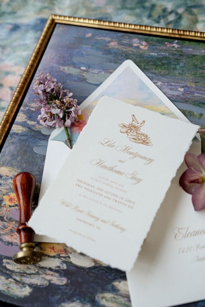 Monet inspired wedding invitation suite flat lay with watercolor envelope liner, wax seal, velvet ring boxes, and garden florals at Wild Roots Lockhart Texas by Austin wedding photographer Andrea Jang