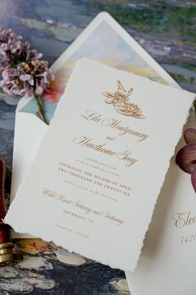 Monet inspired wedding invitation suite flat lay with watercolor envelope liner, wax seal, velvet ring boxes, and garden florals at Wild Roots Lockhart Texas by Austin wedding photographer Andrea Jang