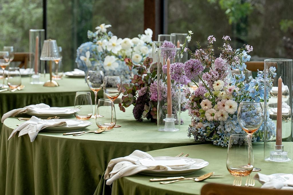 Monet inspired wedding reception tablescape with sage green velvet linens, impressionist floral centerpieces, and peach taper candles at Wild Roots Lockhart Texas, photographed by Austin wedding photographer Andrea Jang