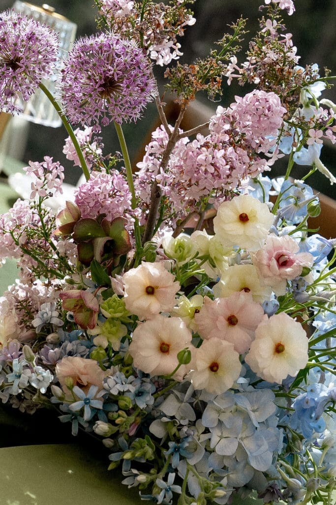 Close up of Monet inspired wedding floral arrangement with allium, lilac, blue hydrangea, blush lisianthus, and ranunculus at Wild Roots Texas Hill Country wedding venue