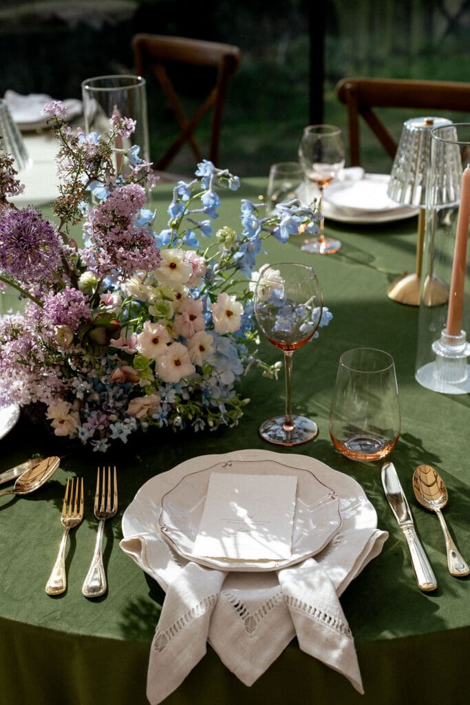 Monet inspired wedding reception tablescape with sage green velvet linens, impressionist floral centerpieces, and peach taper candles at Wild Roots Lockhart Texas, photographed by Austin wedding photographer Andrea Jang
