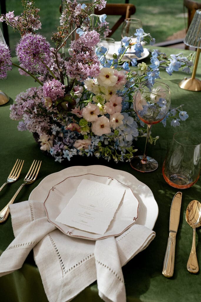 Monet inspired wedding reception tablescape with sage green velvet linens, impressionist floral centerpieces, and peach taper candles at Wild Roots Lockhart Texas, photographed by Austin wedding photographer Andrea Jang