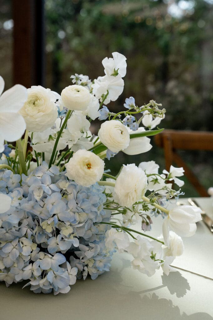 Close up of Monet inspired wedding floral arrangement with allium, lilac, blue hydrangea, blush lisianthus, and ranunculus at Wild Roots Texas Hill Country wedding venue