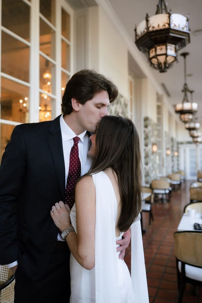 Engaged couple standing beneath ornate chandeliers in the marble lobby of the St. Anthony Hotel in San Antonio