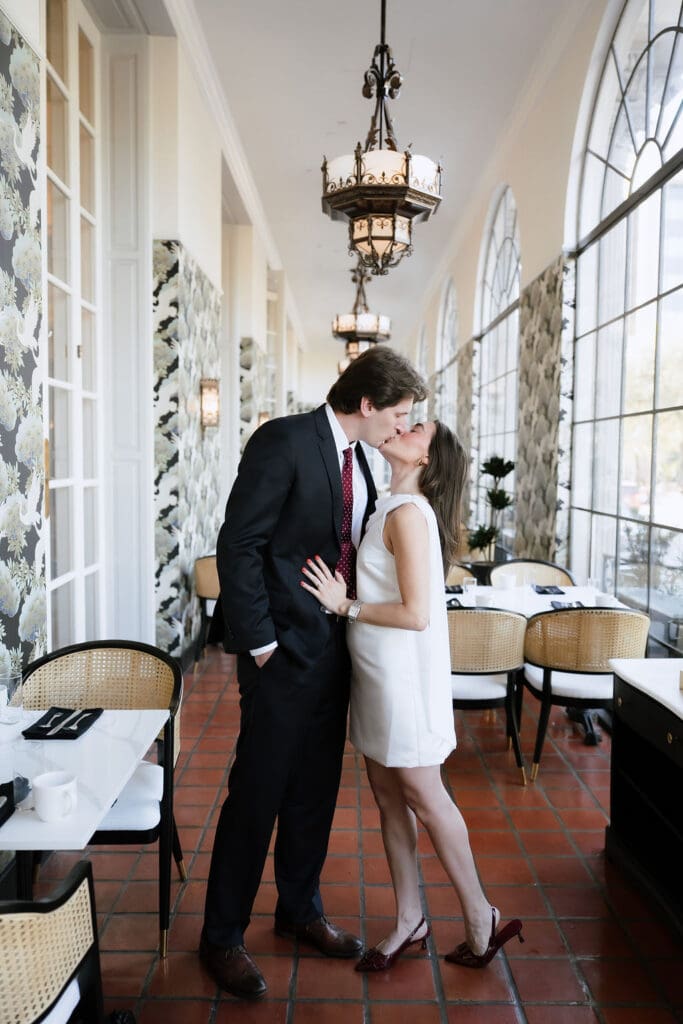 Engaged couple standing beneath ornate chandeliers in the marble lobby of the St. Anthony Hotel in San Antonio