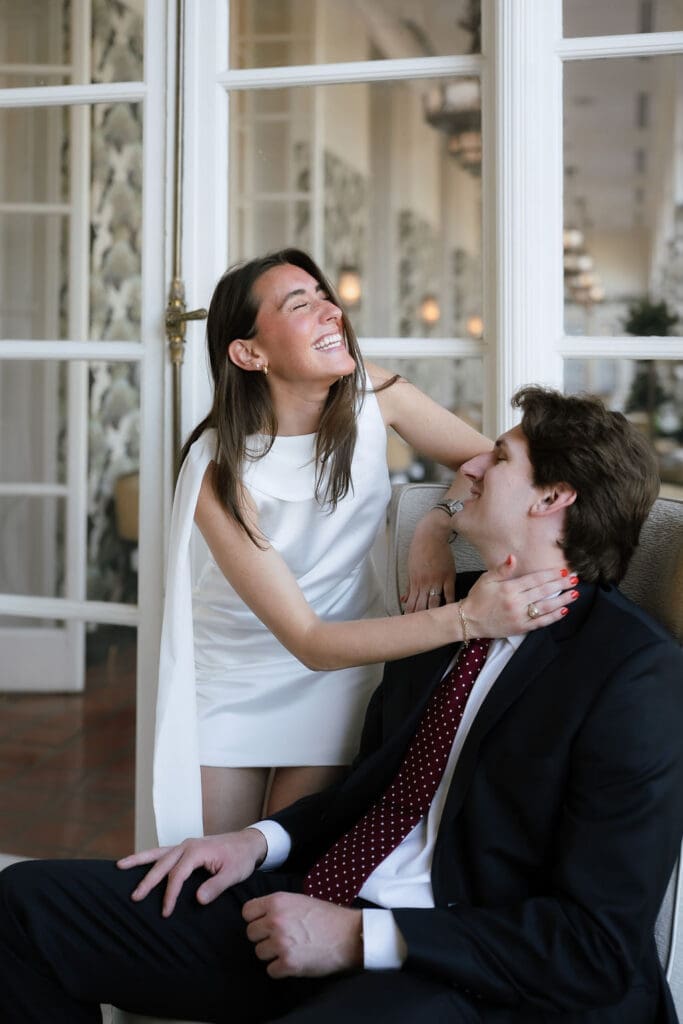 Engaged couple standing beneath ornate chandeliers in the marble lobby of the St. Anthony Hotel in San Antonio