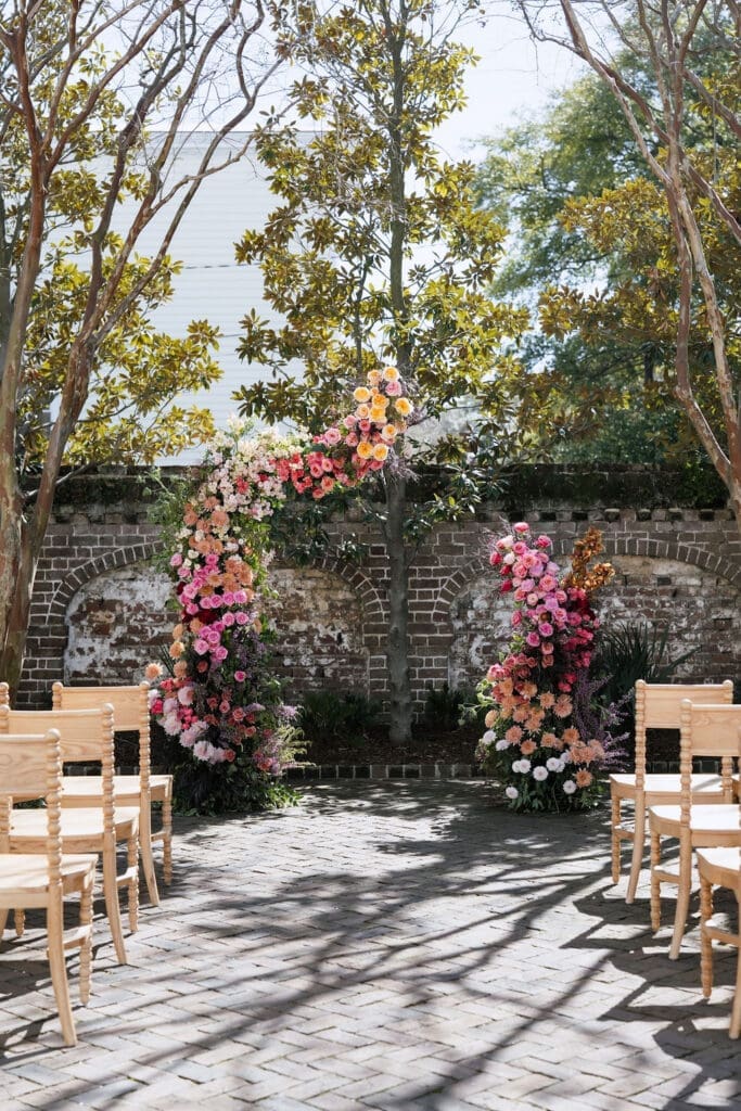 Charleston romance editorial lush floral ceremony arch with pink coral and peach blooms at The Gadsden House
