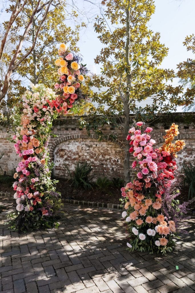 Charleston romance editorial lush floral ceremony arch with pink coral and peach blooms at The Gadsden House