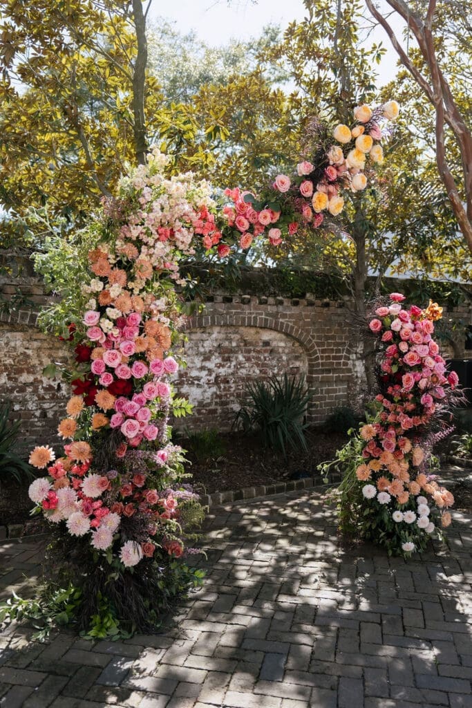Charleston romance editorial lush floral ceremony arch with pink coral and peach blooms at The Gadsden House