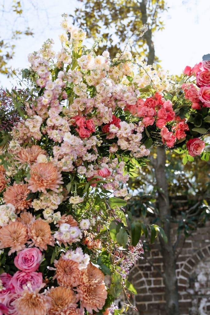 Lush floral ceremony arch with pink coral and peach blooms at The Gadsden House Charleston romance editorial