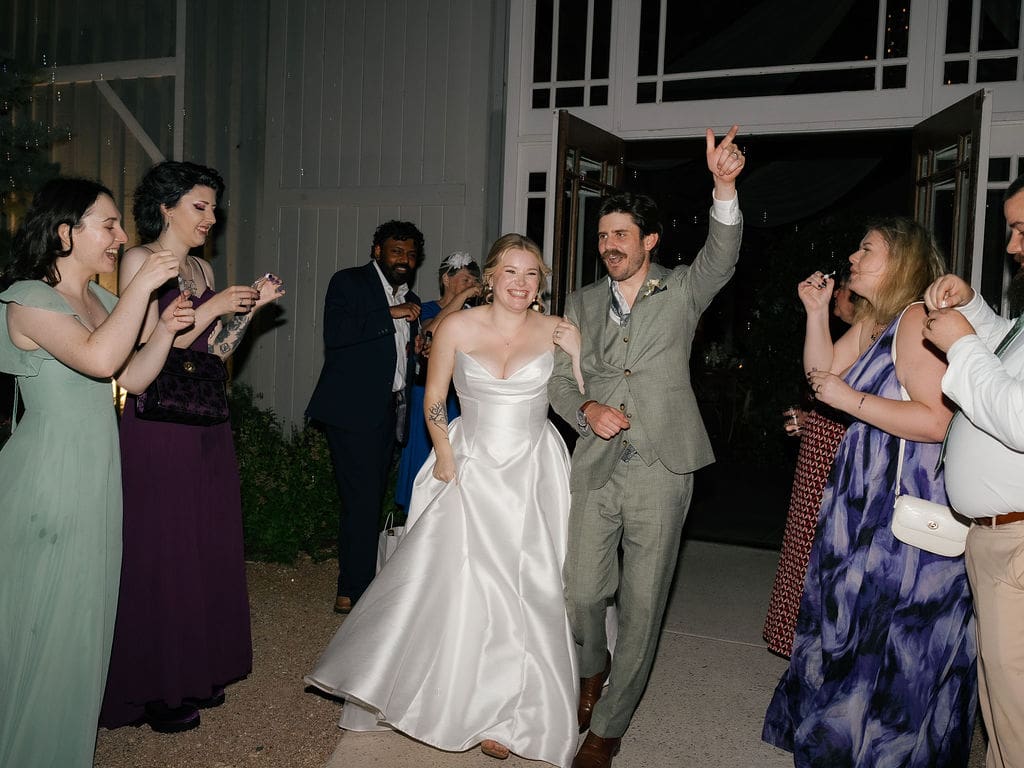 Bride and groom waving goodbye during their wedding send-off