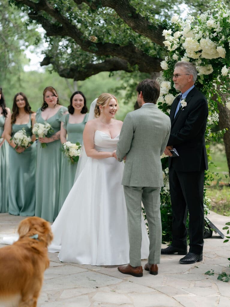 Couple holding hands during their outdoor Texas Hill Country wedding ceremony